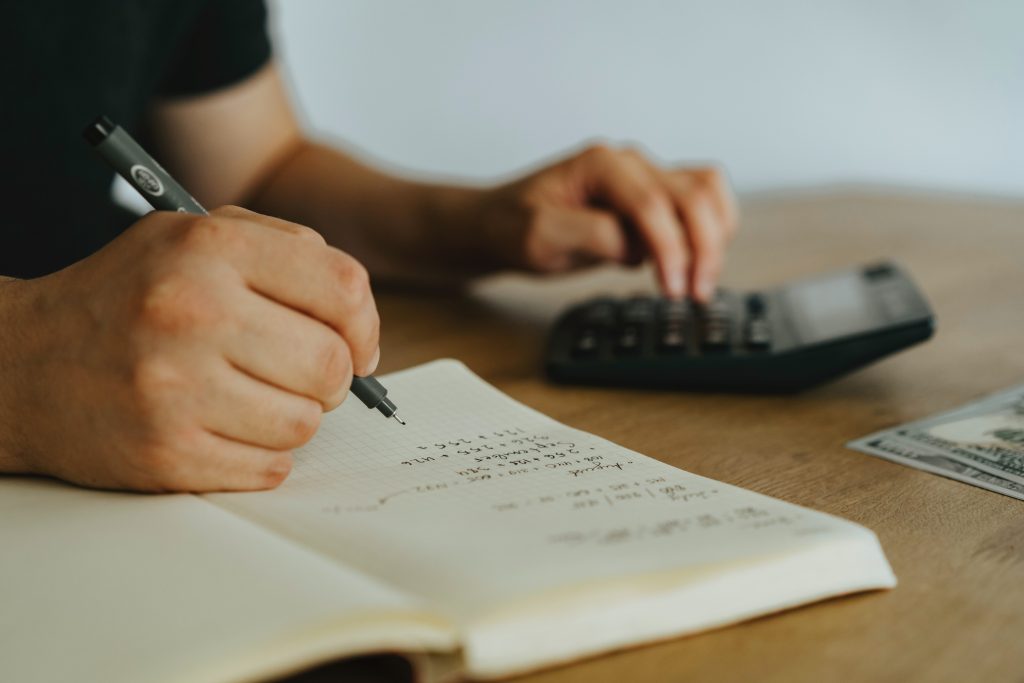 accountant writing his computations the are from the calculator to his notebook