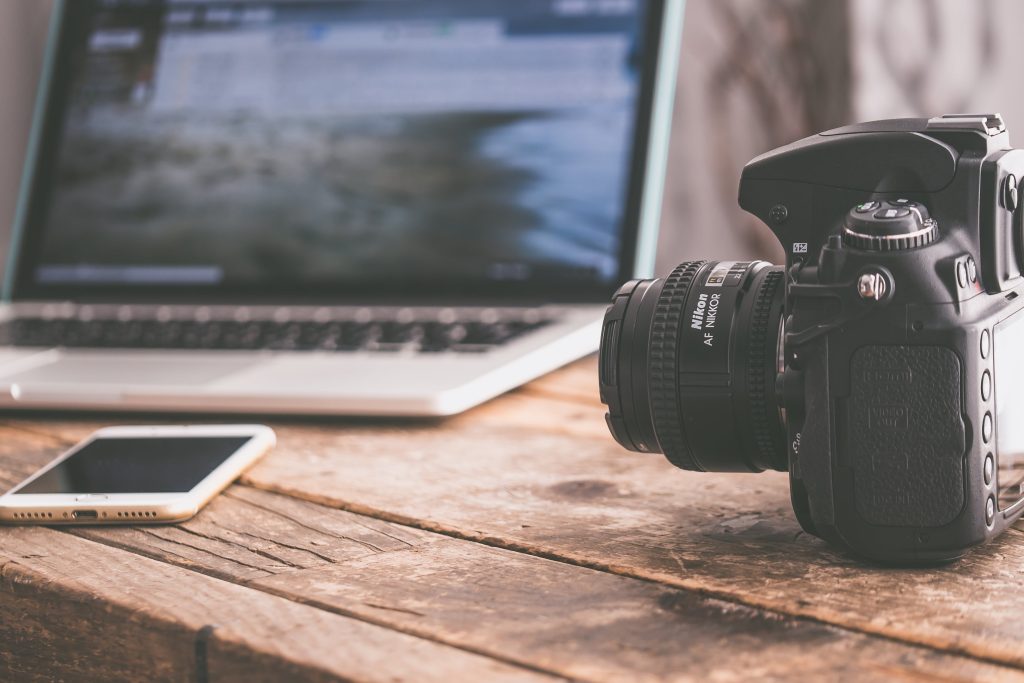 digital camera beside a mobile phone and laptop