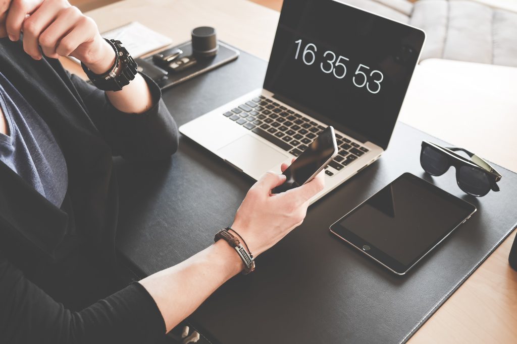 laptop showing current time while an accountant checks her phone