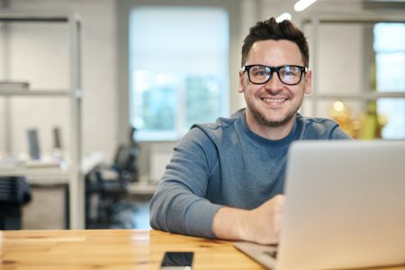 accountant smiling brightly while using his laptop