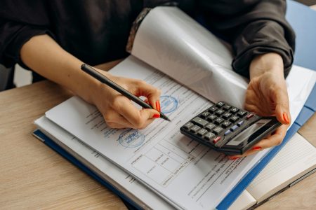 accountant using a calculator while filing up the tax return form